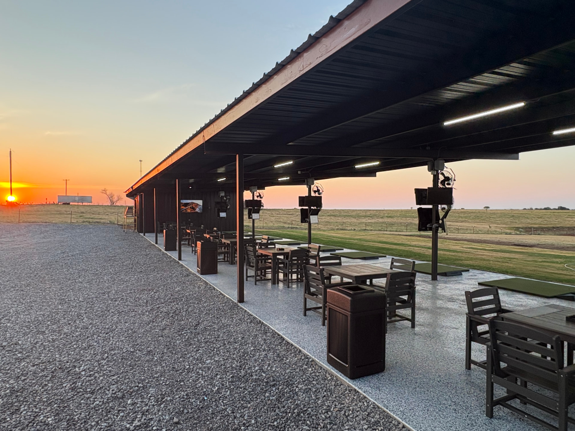 The Back Nine covered outdoor Toptracer driving range at sunset